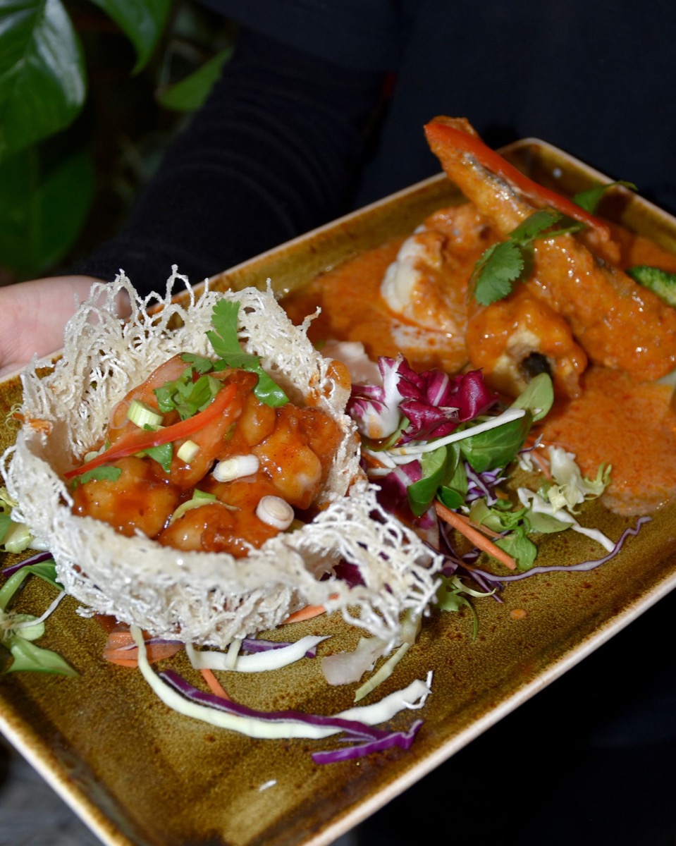 A plate of prawns in curry sauce beside a crisp noodle-nest starter, served at Olive & Thai.