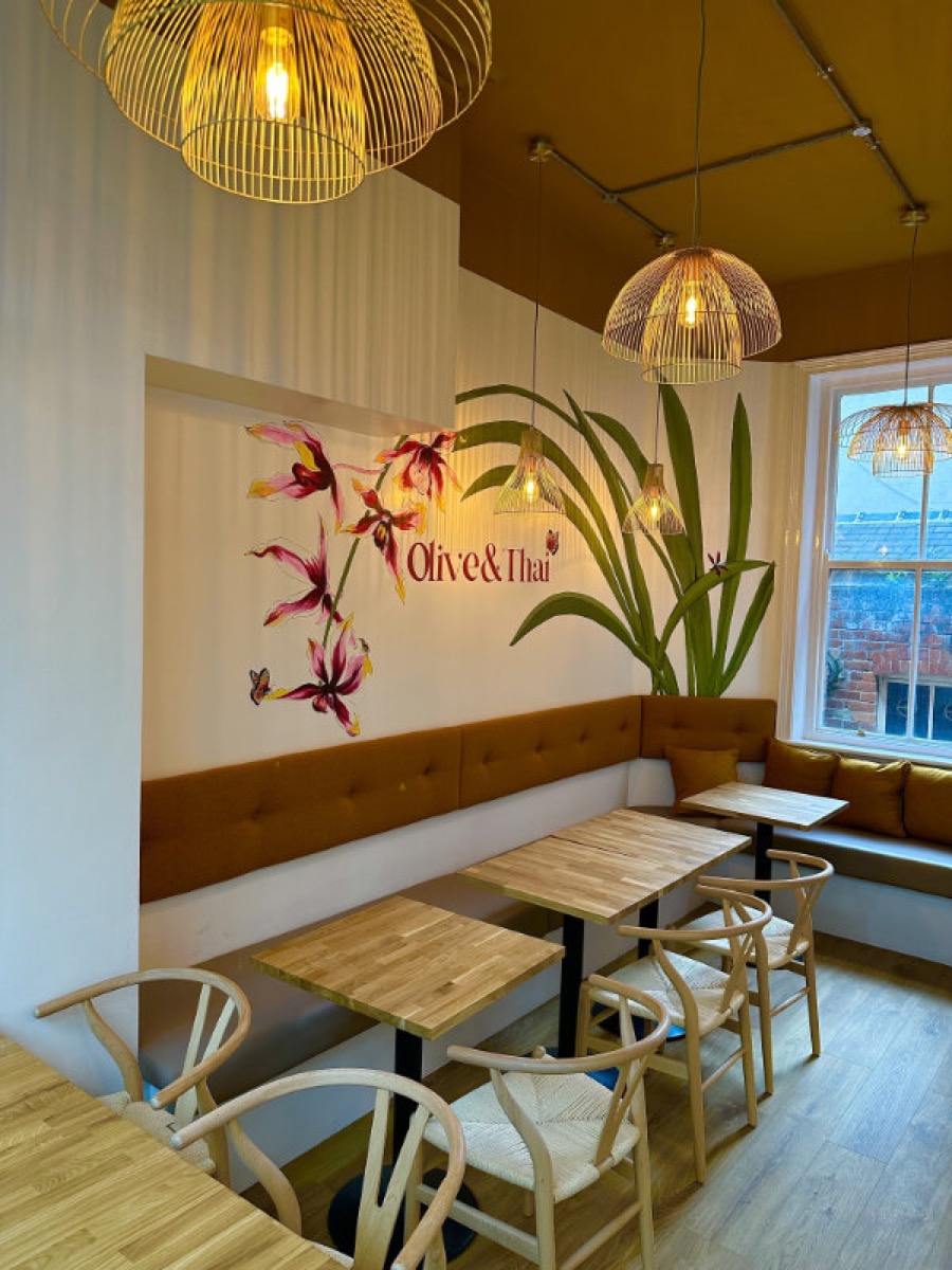 The dining room at Olive & Thai: an ochre ceiling, tan banquette seating and a hand-painted orchid mural.